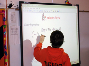 Student writes on a smartboard